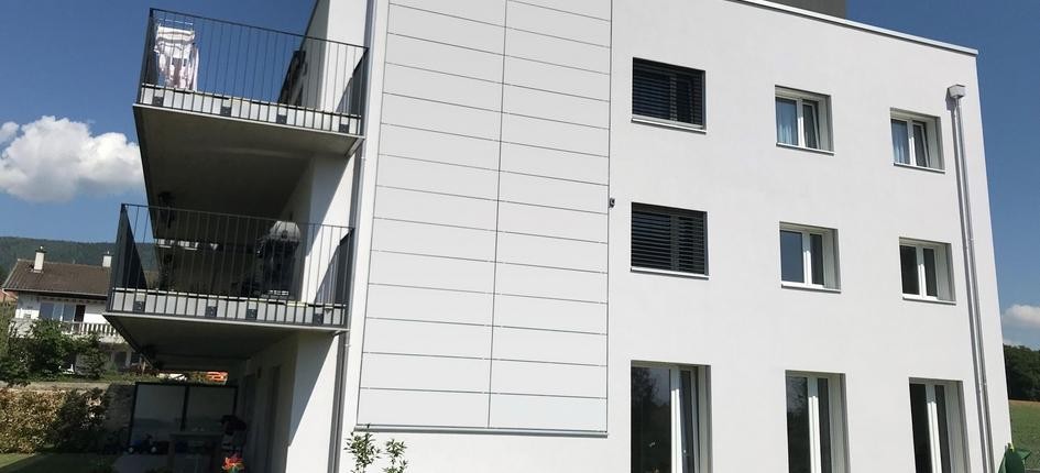 Weisse Photovoltaik-Module an einer Gebäudefassade integrieren sich quasi nahtlos in die architektonische Gestaltung.